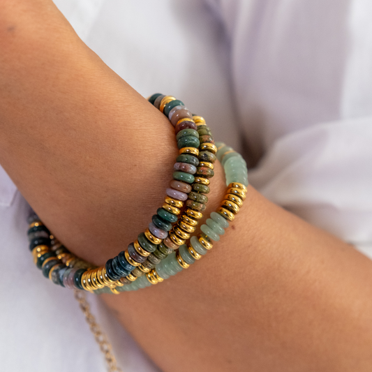 Stack of colorful beaded bracelets on a wrist with a blurred white background