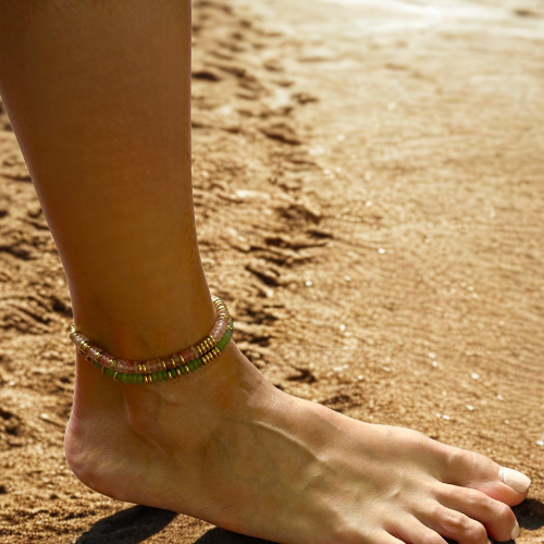 Foot with a beaded anklet on a sandy background